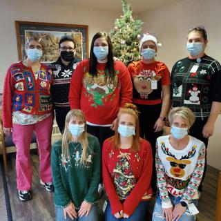 A joyful team celebrating the holiday season in their festive ugly sweaters and masks.