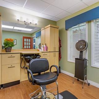 A cozy hair salon interior with a styling chair, mirror, and classic decor.