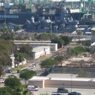 A view of a bustling port area with shipping containers and urban infrastructure.