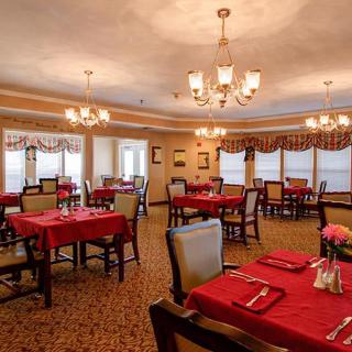 A formal dining room with red tablecloths and elegant chandeliers.