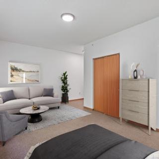 A modern bedroom featuring a cozy seating area, neutral color palette, and stylish decor.