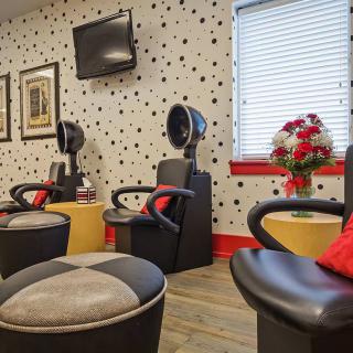 A modern salon interior with styling chairs and hair dryers against polka dot wallpaper.