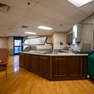 An empty cafeteria kitchen with a wooden counter and chairs.