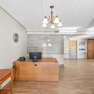 A spacious and well-lit office area featuring a wooden desk, computer setup, and elegant lighting.