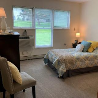 A cozy bedroom with a large window, bed, and soft lighting.