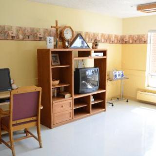 A cozy living room with an entertainment center, complete with a television and a computer desk.