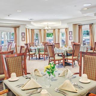 A well-lit dining room with elegantly set tables and comfortable chairs.
