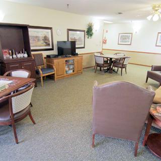 A cozy room with several tables, chairs, a television, and wall decorations.