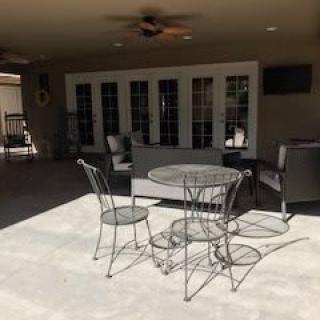 A sunny patio with outdoor seating arrangements, including a table and chairs.