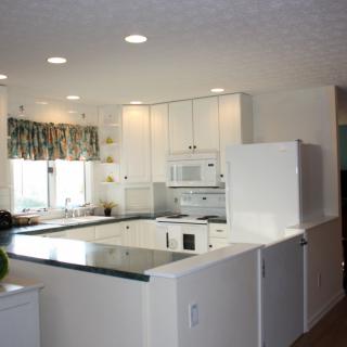 A modern kitchen with white cabinetry, appliances, and bright lighting.