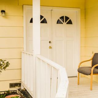 A cozy porch with a chair and a double door on a yellow house.