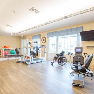 A well-equipped rehabilitation therapy room featuring various exercise equipment and a wheelchair.