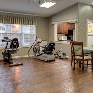 A small indoor gym area with exercise equipment and a table with chairs.
