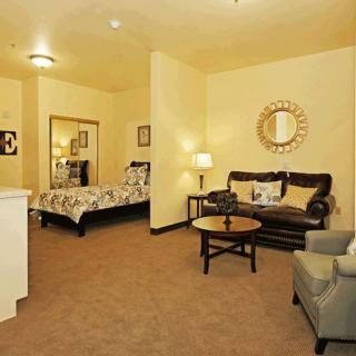 A cozy living space featuring a sofa, armchair, bed, and decorative elements.