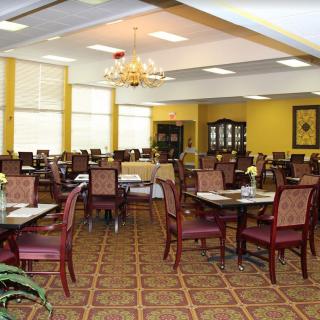 A spacious and elegant dining room with neatly arranged tables and chairs, illuminated by a chandelier.