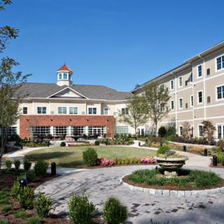 A well-maintained residential building with a landscaped courtyard under a clear blue sky.