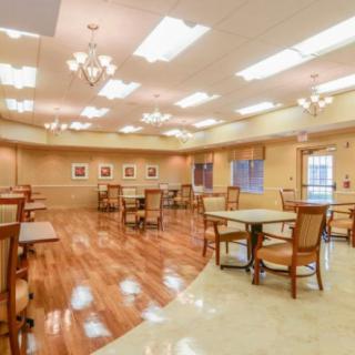 A spacious and well-lit dining area with wooden floors, neatly arranged tables and chairs.