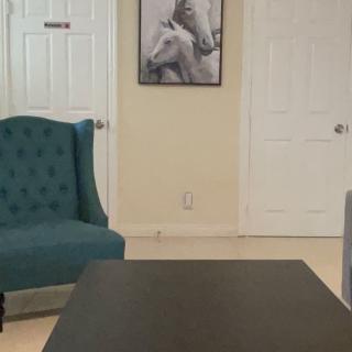 A cozy living room with a teal armchair, a coffee table, and horse-themed artwork on the wall.