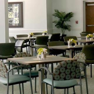 A modern dining area with neatly arranged tables and chairs, adorned with small floral centerpieces.