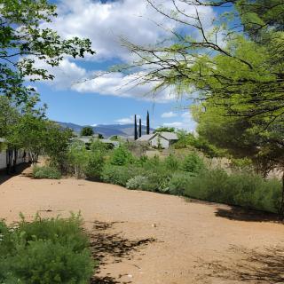 A scenic view of a desert landscape with greenery and church spires in the distance under a blue sky with clouds.