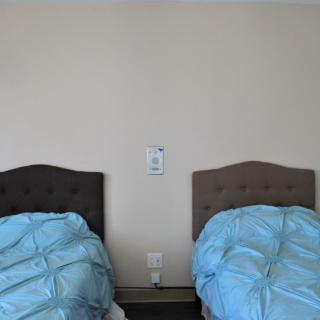 A minimalist bedroom with twin beds featuring blue bedding and simple headboards.