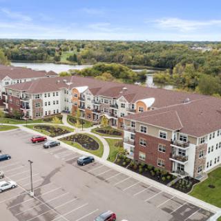 A scenic aerial view of a modern apartment complex surrounded by greenery and a parking area.