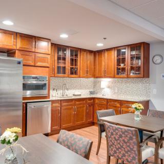 A modern kitchen with wooden cabinets, stainless steel appliances, and a dining area decorated with flowers.