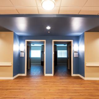 A modern hallway featuring two elevators with bright lighting and wooden flooring.