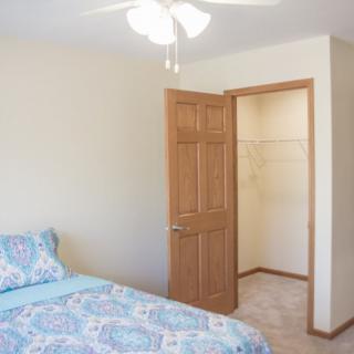 A simple bedroom with a bed, closet, and ceiling fan.