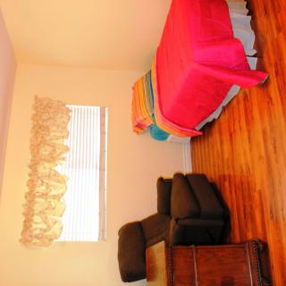 A cozy bedroom with a single bed and an armchair on a wooden floor.