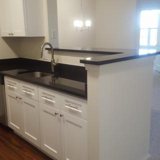 Modern kitchen with black countertops and white cabinets.