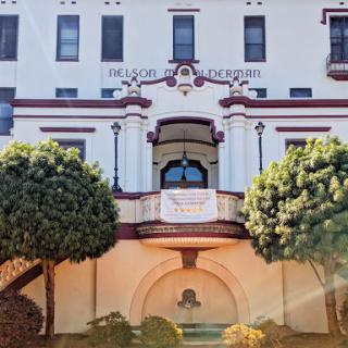 A beautifully designed historic building with decorative architecture, surrounded by lush greenery.