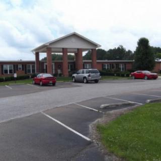 A brick building with a parking lot and several cars in front.