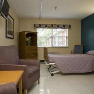 A hospital room with a bed, a chair, and a television.