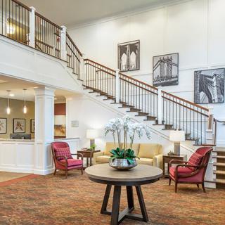 A spacious lobby with a grand staircase, comfortable seating, and elegant decor.