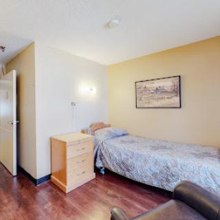 A cozy single bedroom featuring a simple design with wooden flooring and minimalist decor.