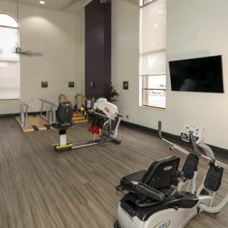A well-equipped fitness center with exercise machines and a TV.