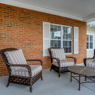 A cozy outdoor patio area with wicker chairs and a table set against a brick wall.