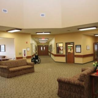 The image shows a lobby area with couches, carpeted flooring, and hallways branching off.