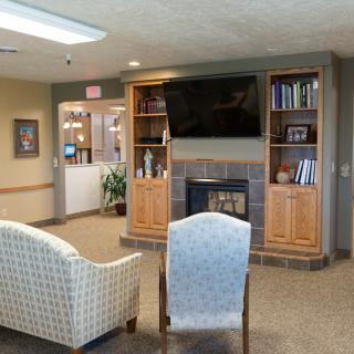 A cozy living room with a TV, fireplace, and bookshelves, featuring comfortable seating.