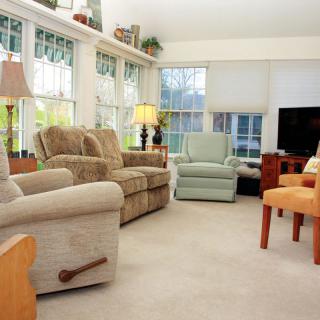 A cozy and well-lit living room with comfortable seating and large windows.