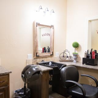 An interior view of a hair salon featuring a styling station with a chair and mirror.