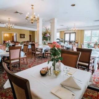 An elegant dining room with neatly set tables, chandeliers, and classic decor.