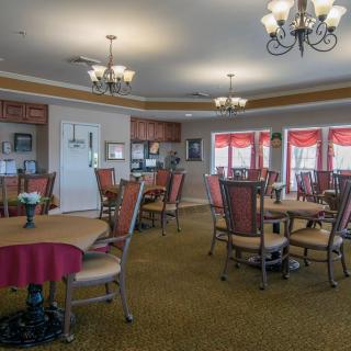 A well-decorated dining room featuring multiple tables and chairs, with elegant chandeliers hanging from the ceiling.