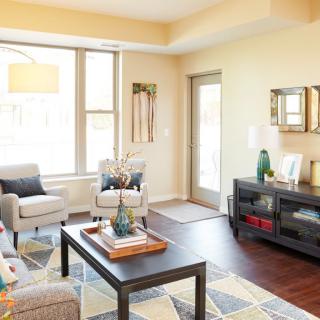 A modern living room with natural light, featuring stylish furniture and wooden flooring.