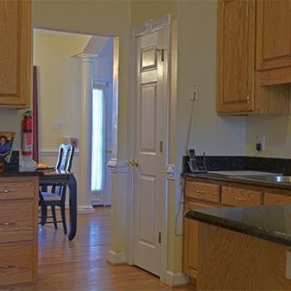 A view of a kitchen with wooden cabinets and a doorway leading to a dining area.