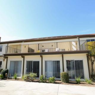 A two-story residential apartment building with balconies and large windows on a clear day.