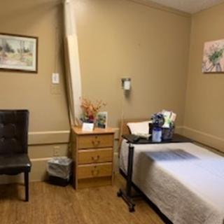 A cozy hospital room featuring a bed, chair, and personal touches.