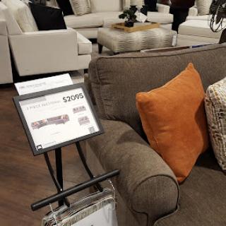 A cozy living room setup featuring a sofa with an accent pillow, displayed in a furniture store.