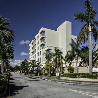 A modern residential building surrounded by palm trees under a clear blue sky.